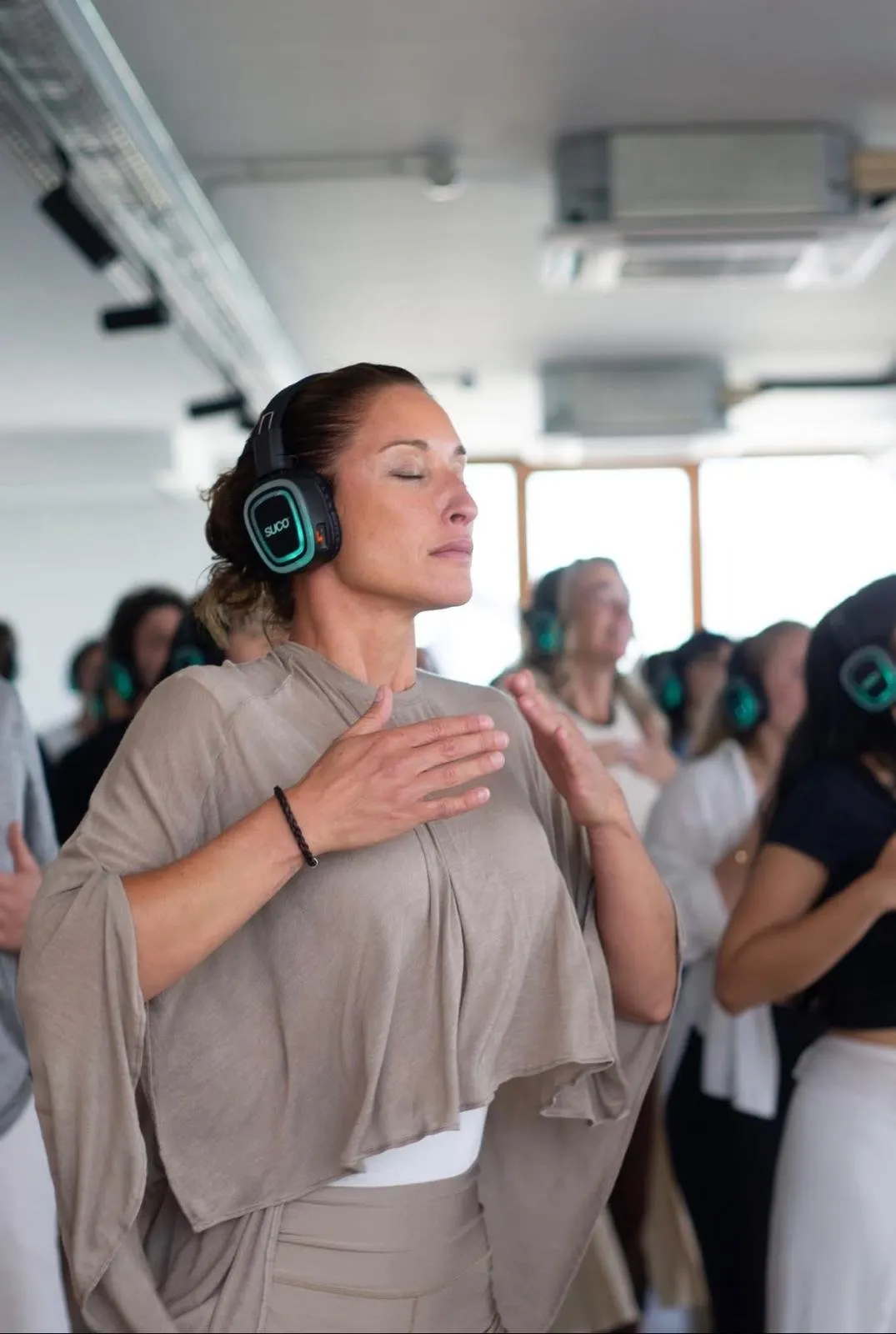 SUCO active meditation with wireless headphones, hand on the heart